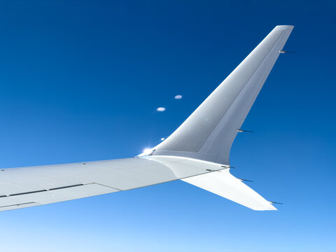 Clear blue sky above airplane wing and tail fin