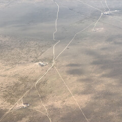 Fototapeta premium Aerial view of vast desert with winding roads and sparse vegetation