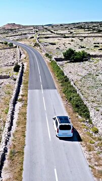 Aerial shot of car driving between the dry stone fence