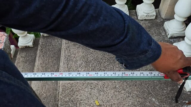 Close up of measuring and marking an iron bar with a tape and marker