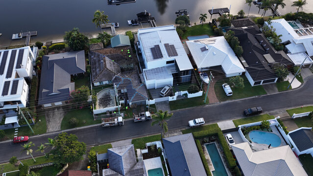Aerial View of Suburban Waterfront Houses with Solar Panels and Roof Repairs