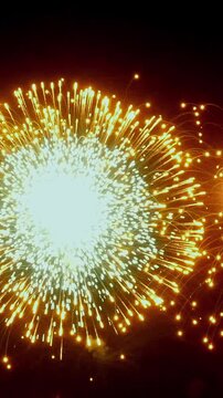 Dazzling fireworks illuminate the Paris sky, creating a vibrant and colorful display during a Summer night celebration. Gold, white, and orange sparkles burst forth.