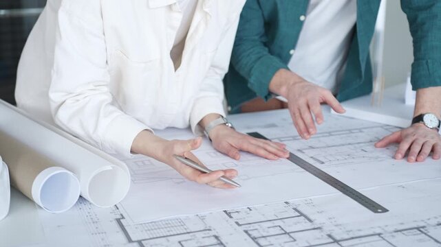 Architects discussing apartment building blueprint at office desk, using drafting tools for new architectural project design. Architecture and business concept