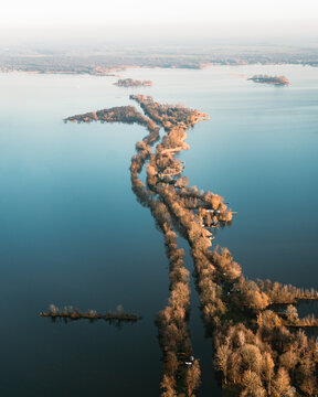 Aerial view of the narrow, tree-lined Scheendijk peninsula extending into the calm waters of the Loosdrecht lakes in Scheendijk, Breukelen, Utrecht, Netherlands.