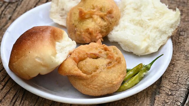 vada pav, mumbai famous vada paav is an indian burger. potato patty is deep fried and stuffed inside a paav or bun like burger, served over a rustic wooden background