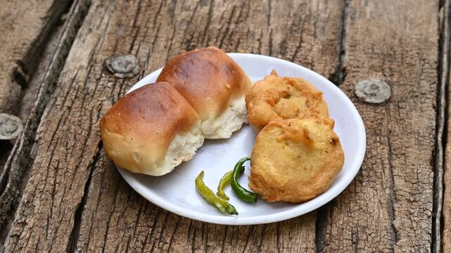 vada pav, mumbai famous vada paav is an indian burger. potato patty is deep fried and stuffed inside a paav or bun like burger, served over a rustic wooden background