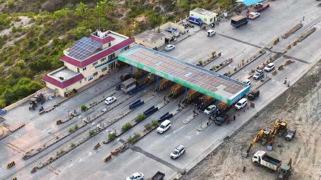Commercial traffic and commuter vehicles at regional highway Fast Tag toll plaza.