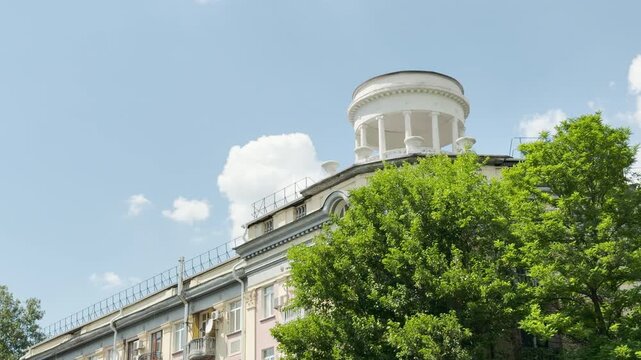 A grand building with a white rotunda stands proudly above green trees in Simferopol, Crimea. The bright sunny sky brings a joyful and serene feeling.