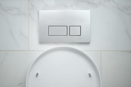 Toilet flush press with buttons on wall. Modern bathroom design with marble tiles.