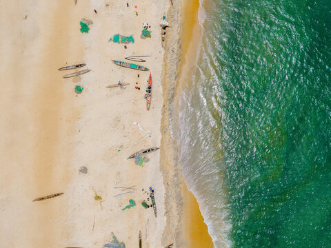 Aerial view of traditional wooden fishing boats and fishermen on the sandy beach in Monrovia, Liberia.