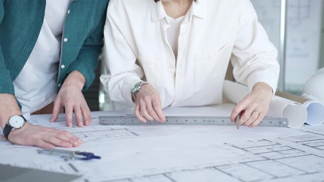 Professional team working together on detailed floor plans, discussing project development, and preparing for future construction. Architecture and business concept