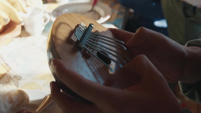 Woman plays musical instrument named Kalimba, or Mbira made of coconut shell