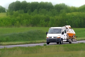 Fototapeta premium Tow truck service helping broken vehicle on road