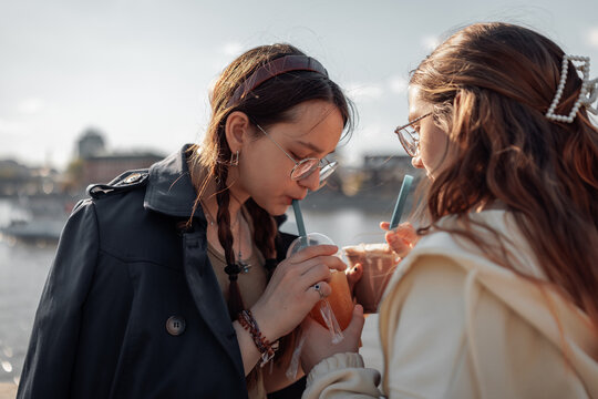 Two teenage girls with long hair and glasses are standing together by