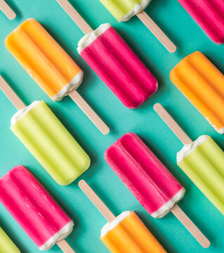 Colorful fruit ice pops in a diagonal pattern on teal background.
