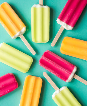 Colorful frozen ice pops on a teal background