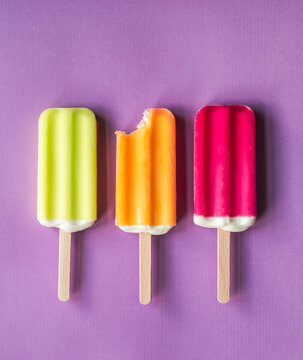 Colorful ice pops lined up with one bitten