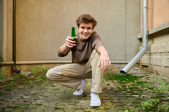 Teenage male with bottle poses outside in city scene. General street portrait with prevention message
