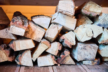 Obraz premium Firewood pieces arranged in neat pile under timber bench in sauna. Close up of dry logs for heating system, warm spa interior and rustic comfort concept
