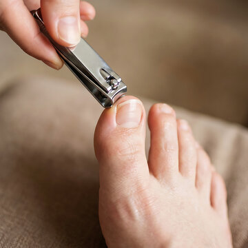 Person trimming toenails with clipper