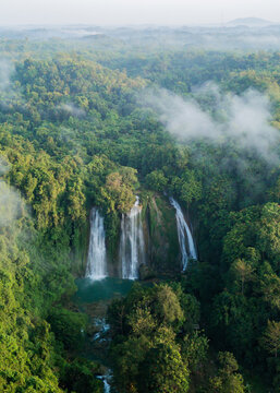 Aerial view of Cikaso Waterfall surrounded by dense tropical jungle and mist in West Java, Indonesia.