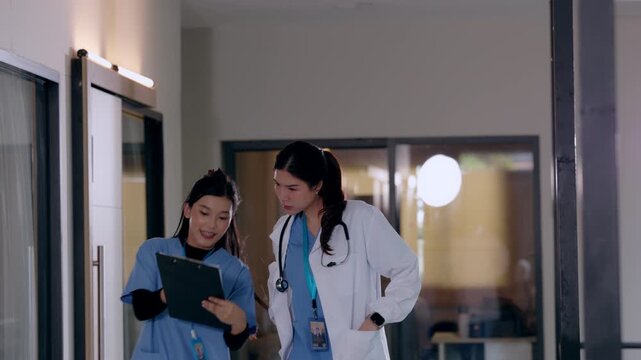 Female doctor nurse clipboard hospital medical healthcare stethoscope asian worker in lab coat and blue scrubs walking hallway corridor with clinical teamwork near glass room