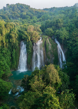 Aerial view of Cikaso Waterfall cascading into a turquoise pool surrounded by dense tropical rainforest in West Java, Indonesia.
