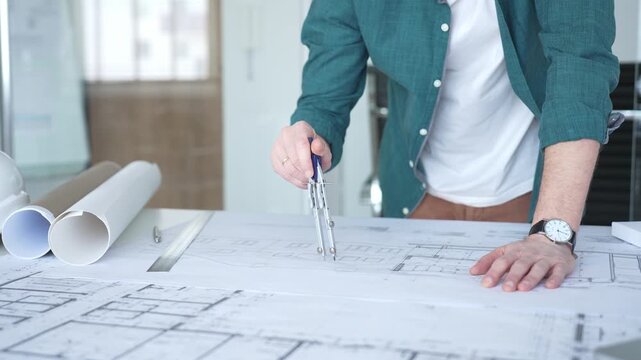Architect working on building blueprint plans, using compass for design and engineering project. Architecture and business concept