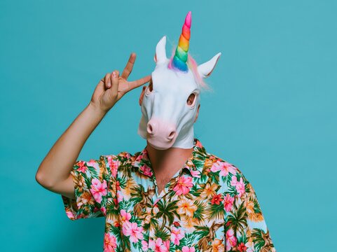 Man wearing unicorn mask and Hawaiian shirt making gesture