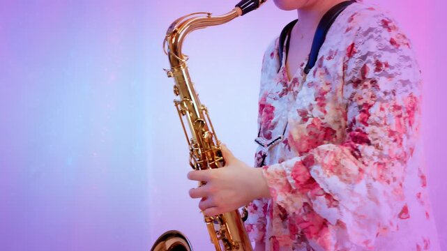 テナーサックスを立って演奏している女性：ピンクっぽい雰囲気・白背景