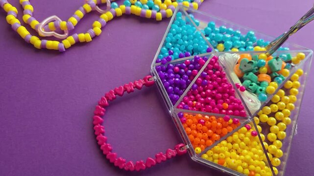 Brightly colored sets of beads, seed beads, and decorative elements in plastic organizers for arts and crafts. Supplies for making jewelry, bracelets, crafts, and educational activities for children.