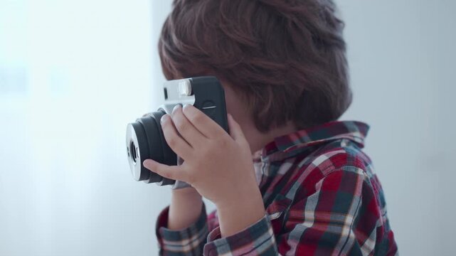 A young boy explores photography with an old camera, learning creativity