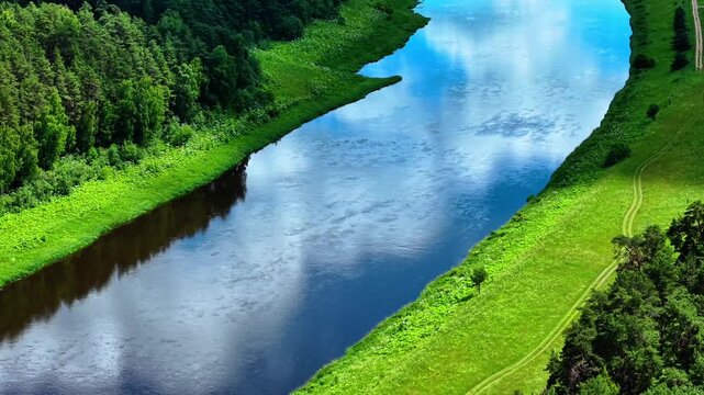Meandering river reflecting cloud patterns surrounded by lush green vegetation