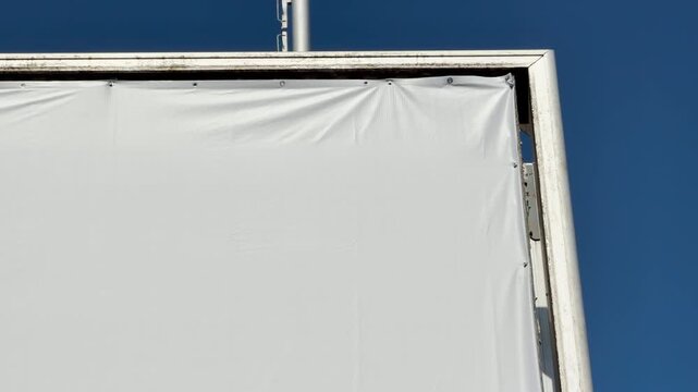 A blank white banner is tightly mounted on a metal frame against a bright blue sky. This clean, minimalist scene feels calm, organized, and full of potential.
