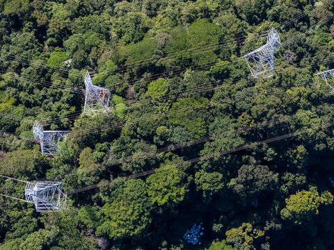 Aerial view of high-voltage power lines stretching across a dense tropical forest canopy in Rio de Janeiro, State of Rio de Janeiro, Brazil.