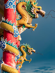 Obraz premium Intricately carved dragons adorn vibrant pillars under a cloudy sky