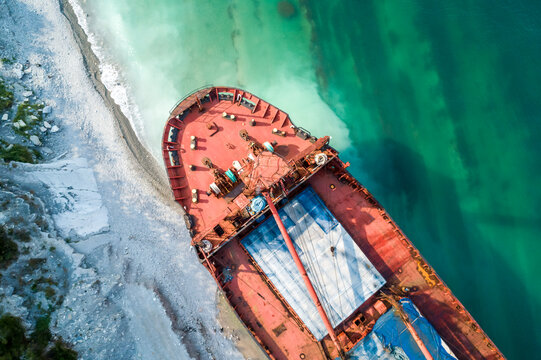 Aerial top down view of a bow part of an abandoned bulk-carrier dry cargo ship washed ashore after a storm