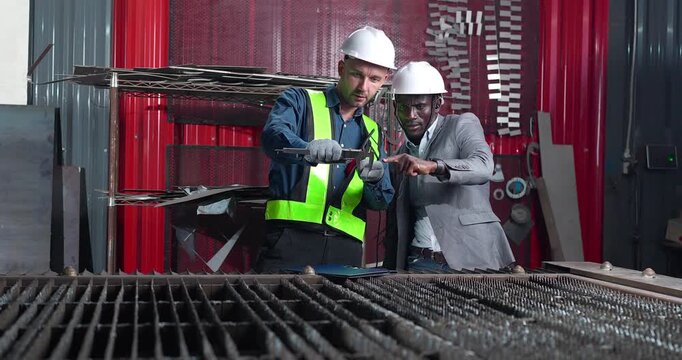 Sales engineer briefs a client in a metal workshop, using sample parts and technical references to present fabrication capabilities, customization options and production solutions.
