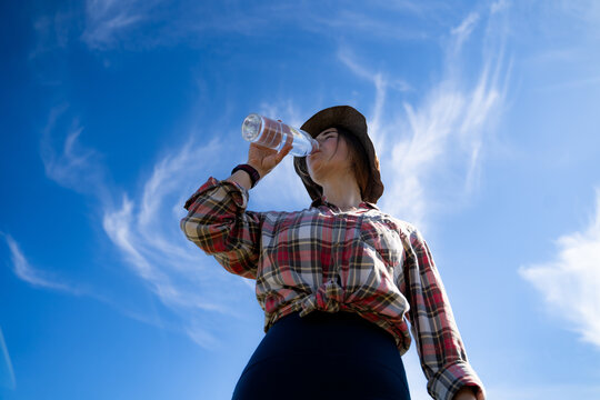 Female traveler drinking water during a mountain hike. Low-angle outdoor portrait emphasizing hydration, wellness and active living.