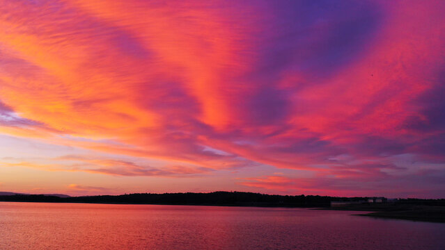 Aerial view of Lake Samsonvale featuring vibrant orange and purple sunset clouds reflecting over the calm water, City of Moreton Bay, Queensland, Australia.