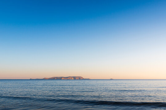 Scenic view of the calm Mediterranean sea surface with the uninhabited island of Dia on the horizon under a clear blue sky in Crete, Greece