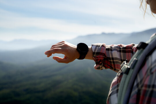 Smartwatch on a woman&rsquo;s wrist during a mountain hike. Wearable technology, fitness tracking and outdoor lifestyle concept.