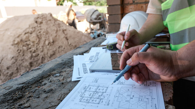 Construction professionals reviewing blueprints and digital plans on a building site