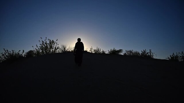 Silhouette of a man walking on hill against sunset sky