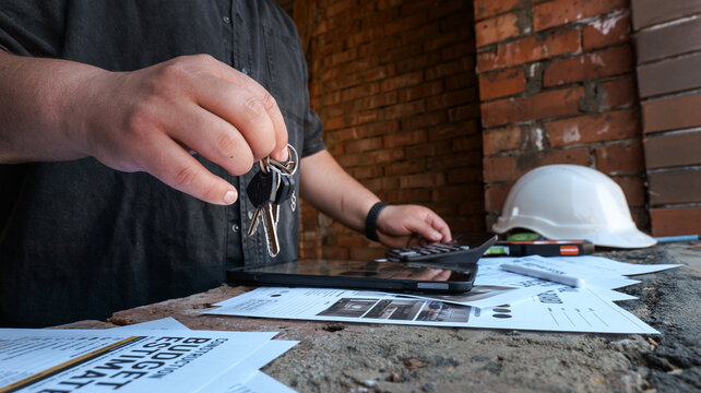 Construction budget estimate with keys and calculator on a brick wall background