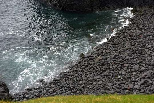Black basalt pebble beach lined by dark ocean waves at Arnarstapi, Iceland