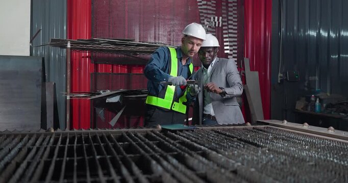 Sales engineer briefs a client in a metal workshop, using sample parts and technical references to present fabrication capabilities, customization options and production solutions.
