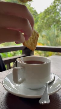 Dipping a Biscuit into a Cup of Tea on a Balcony in Tanarimba Janda Baik Malaysia