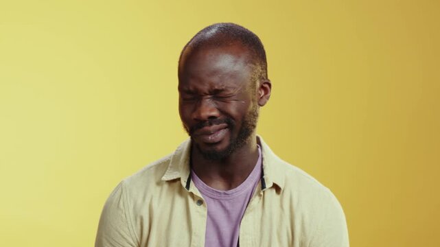 A bearded man does comedy on a yellow background, engaging viewers