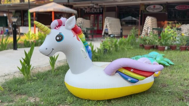 Inflatable unicorn pool float displayed outdoors near a resort area. Summer vacation, family fun, swimming pool accessory, leisure, travel and holiday lifestyle concept.
